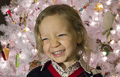Photograph of a young boy in front of a Christmas Tree